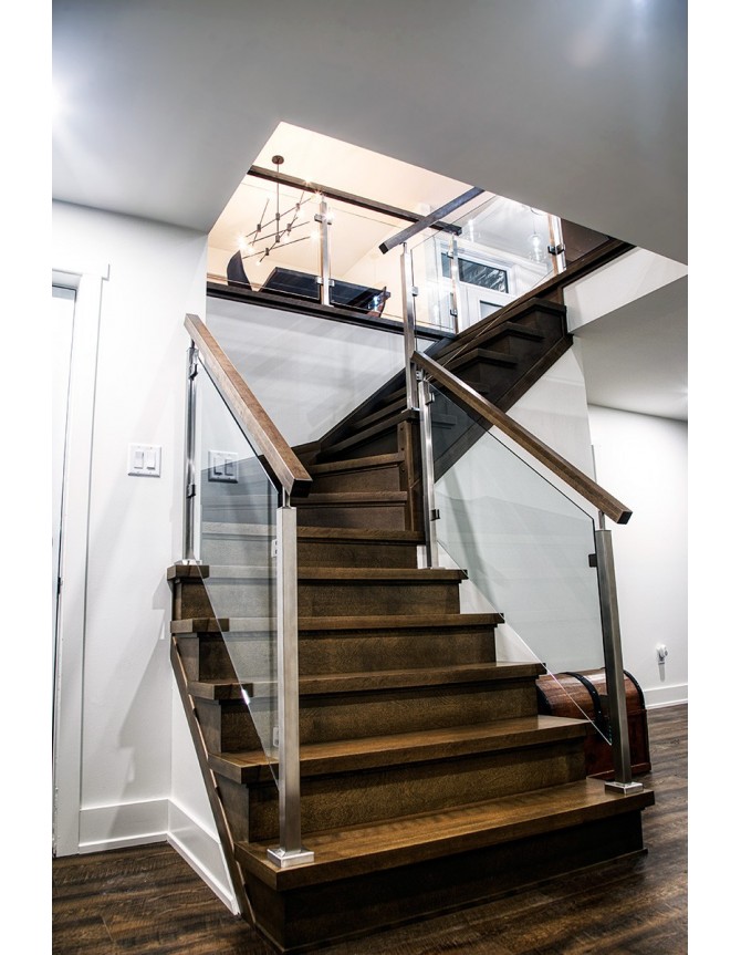 Escalier intérieur avec marches en bois, garde-corps en verre et poteaux en acier
