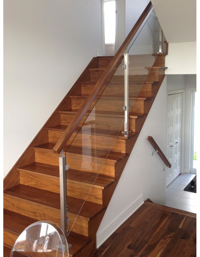 Interior wood staircase with glass railing and stainless steel posts